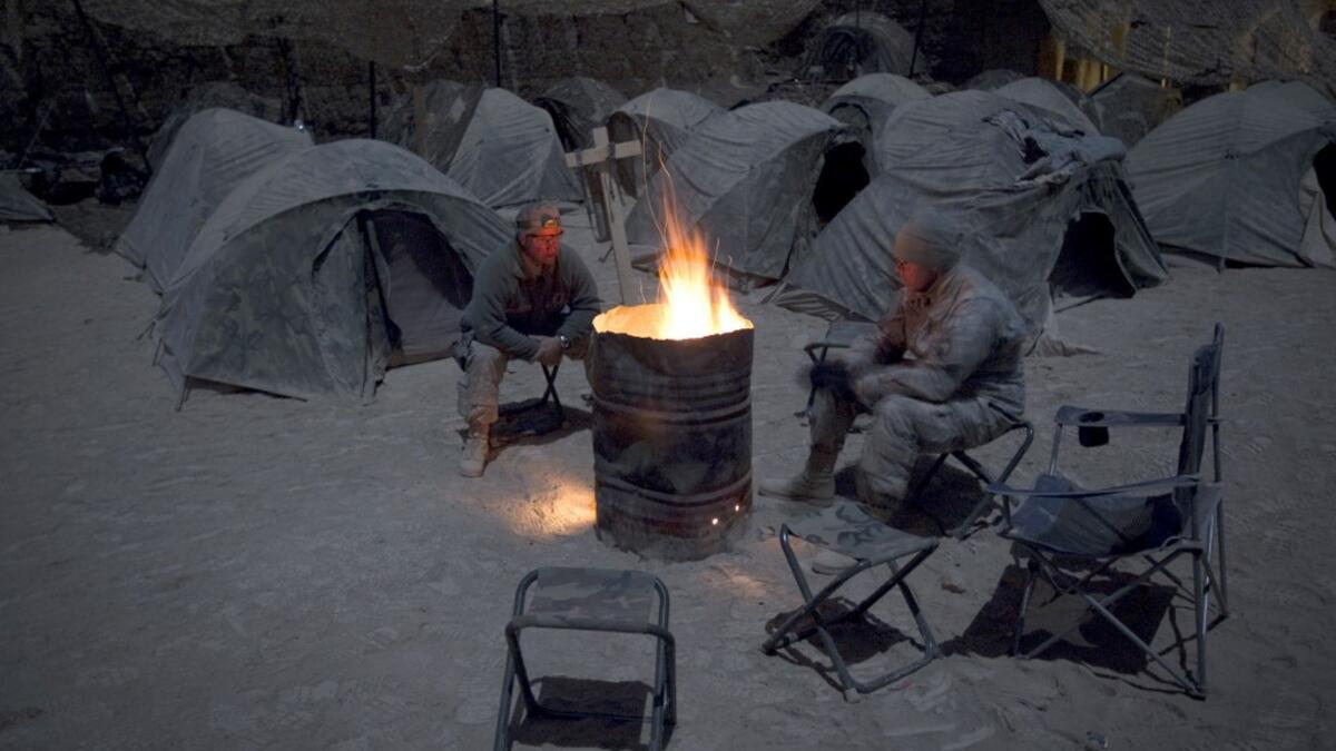 In this file photo taken on December 19, 2010, US soldiers from Alpha Troop 1-75 Cavalry 2nd Brigade 101st Airborne Devision warm themselves around a bonfire at the Sabloghay Camp in Zari district of Kandahar province. American forces have started pulling out of two bases in Afghanistan, a US official said on March 10, 2020 the day peace talks between Kabul and the Taliban were due to start despite widespread violence and a political crisis. The United States is keen to end its longest-ever conflict, and un