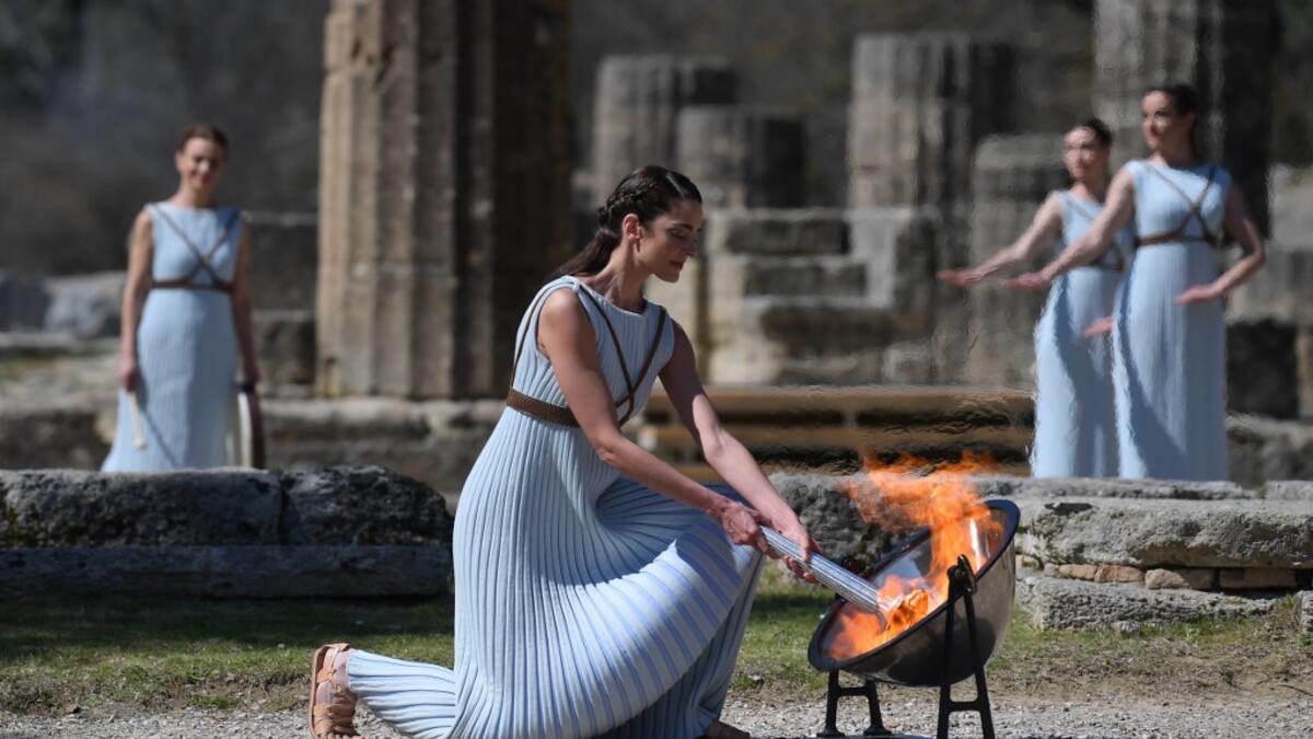A woman dressed as a priestess lits the Olympic flame during the Olympic ceremony in ancient Olympia, ahead of Tokyo 2020 Olympic Games on March 12, 2020. ARIS MESSINIS / AFP