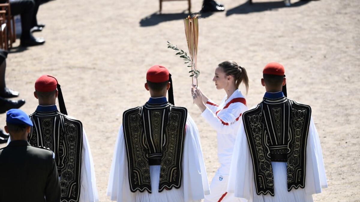 Torchbearer Greece's Anna Korakaki, Rio 2016 gold medallist in the 25m pistol shooting, walks past Greek Evzones Guard as she holds the Olympic flame and an olive branch during the flame lighting ceremony on March 12, 2020 in ancient Olympia, ahead of the Tokyo 2020 Olympic Games. ARIS MESSINIS / AFP
