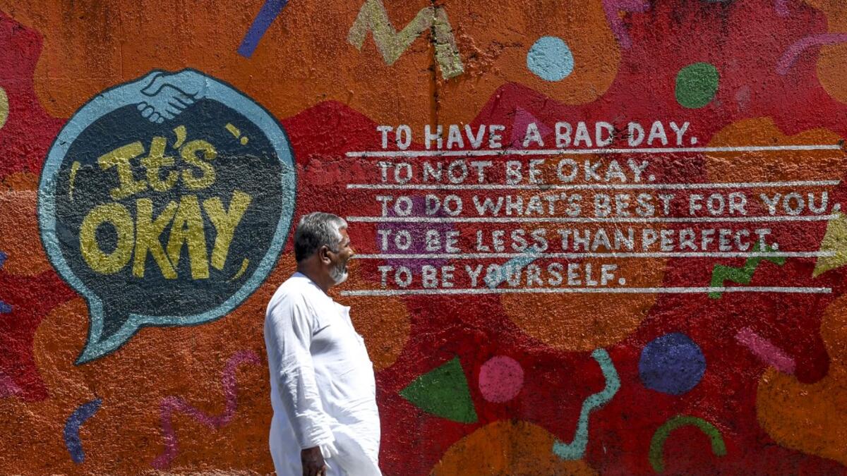 A man walks past a graffiti with a positive message painted on a wall in a street in Mumbai on March 14, 2020. INDRANIL MUKHERJEE / AFP