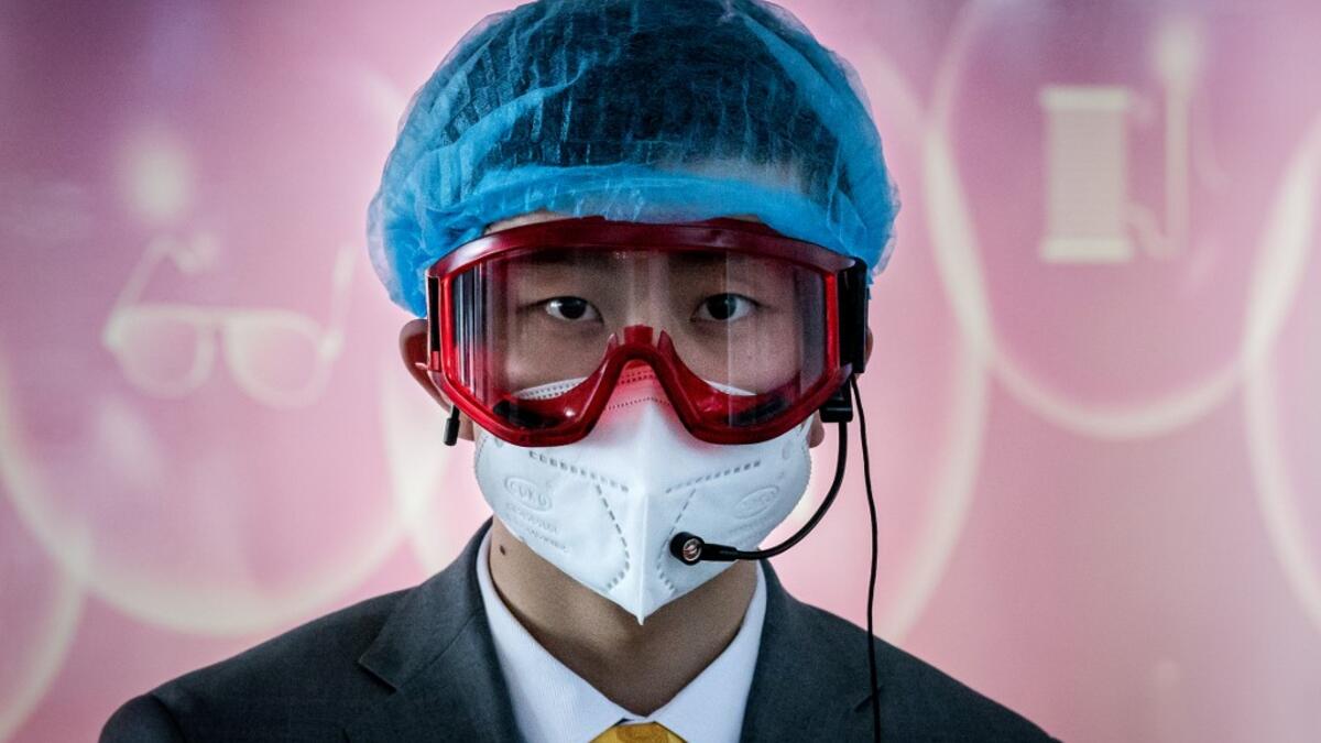 A worker at an information desk wearing protective gear as a preventive measure against the COVID-19 coronavirus looks on at a nearly empty arrivals area at Beijing Capital Airport in Beijing on March 16, 2020. China tightened quarantine measures for international arrivals as the country worries about a rise in imported cases of the deadly coronavirus and anger rages online at how Europe and the United States are handling the pandemic. NICOLAS ASFOURI / AFP