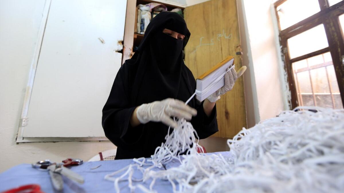 A Yemeni woman makes face masks at a textile factory in the capital Sanaa on March 16, 2020. More than a decade after it shut down, 20 women have brought back to life Yemen's oldest industrial factory to manufacture what could save many lives amid a global pandemic: masks. Mohammed HUWAIS / AFP