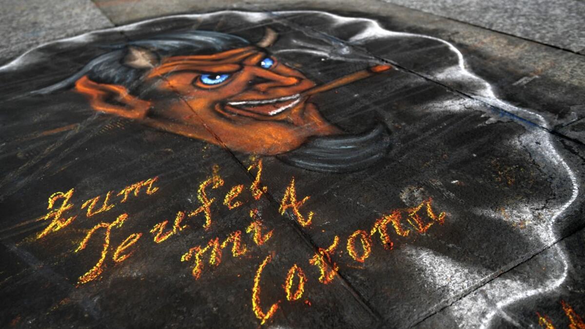 A graffiti 'to hell with corona' is seen in front of the Cologne cathedral on March 17, 2020, western Germany, where restaurants closed, as well as many activities slowed down or came to a halt due to the spread of the novel coronavirus. Ina FASSBENDER / AFP