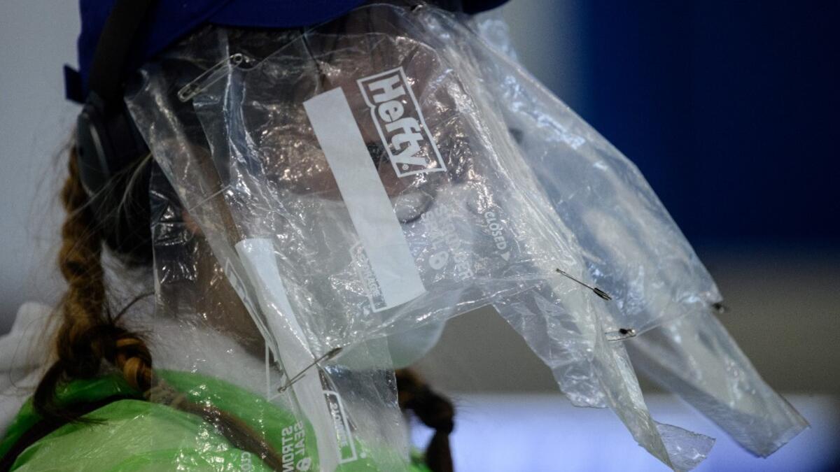A passenger wears a face mask and plastic food bags on her face as a precautionary measure against the COVID-19 coronavirus after landing at Hong Kong’s international airport on March 19, 2020. On March 18, Hong Kong authorities began ordering all arrivals from overseas to wear electronic bracelets, connected to an app to mark your location, and two weeks self-quarantine. ANTHONY WALLACE / AFP