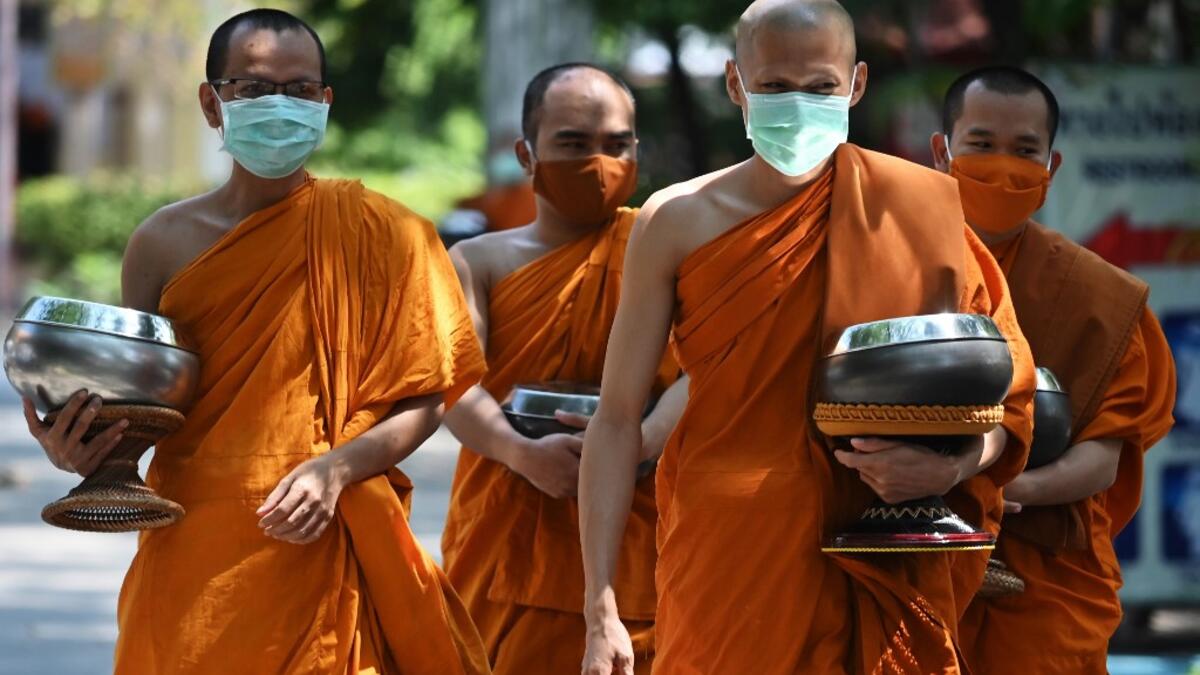 Buddhist monks (back) wear face masks made from recycled plastic bottles, amid concerns over the spread of the COVID-19 coronavirus, at Wat Chak Daeng Buddhist temple in Samut Prakan on March 23, 2020. The plastic wastes are sent to a separate recycling facility processing it into thread materials and woven as special fabric for monks. Lillian SUWANRUMPHA / AFP