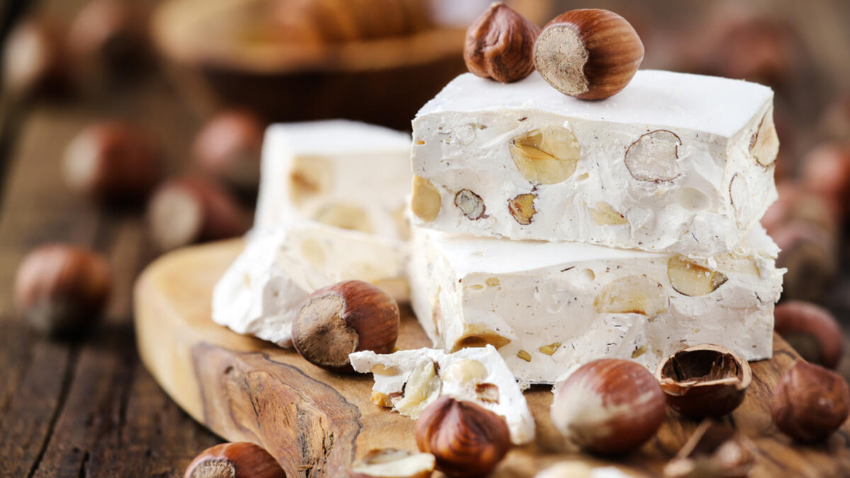 Delicious Italian festive torrone or nougat with hazelnuts on a wood (Shutterstock)