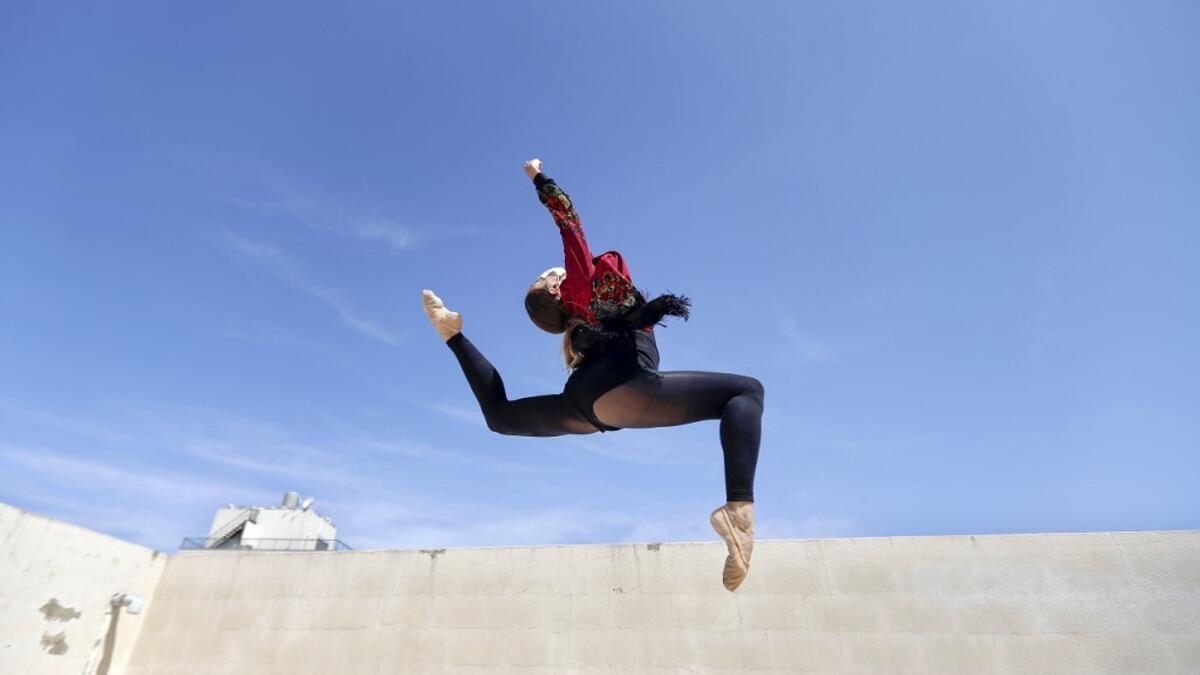 Sherazade Mami, a 28-year-old Tunisian professional dancer and performer at the Caracalla dance theatre and a teacher at the Caracalla dance school, practices while wearing a surgical mask on the roof of her apartment building in the suburb of Dekwaneh on the eastern outskirts of Lebanon's capital Beirut on April 4, 2020. Due to the confinement regulations imposed to combat the COVID-19 coronavirus pandemic, Mami opted to continue practicing on her rooftop to remain in shape. JOSEPH EID / AFP