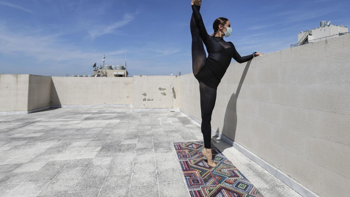 Sherazade Mami, a 28-year-old Tunisian professional dancer and performer at the Caracalla dance theatre and a teacher at the Caracalla dance school, practices while wearing a surgical mask on the roof of her apartment building in the suburb of Dekwaneh on the eastern outskirts of Lebanon's capital Beirut on April 4, 2020. Due to the confinement regulations imposed to combat the COVID-19 coronavirus pandemic, Mami opted to continue practicing on her rooftop to remain in shape. JOSEPH EID / AFP