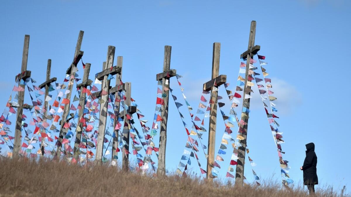 A man stands in front of giant crosses on April 5, 2020 in the town of Achmiany, some 130 km northwest of Minsk, during Palm Sunday celebrations which mark a week before Easter. Sergei GAPON / AFP