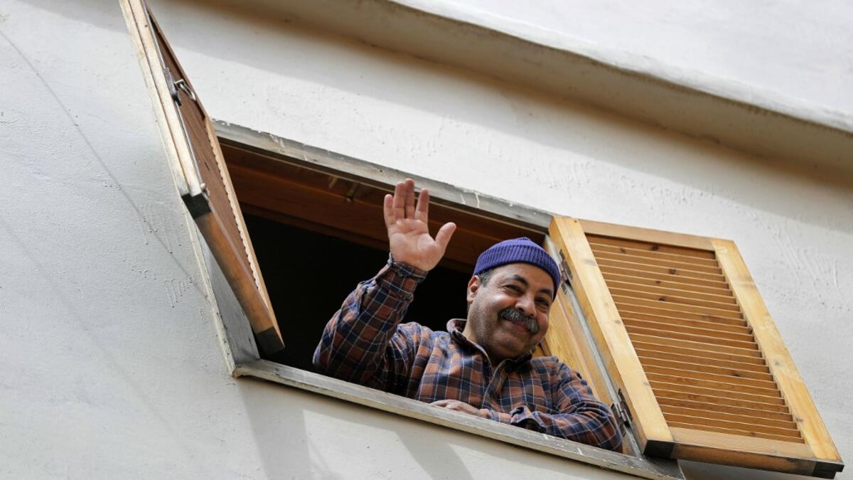 A Lebanese man waves in greeting from his window during confinement at home due to the COVID-19 pandemic, in the historic part of the southern coastal city of Sidon (Saida), on April 6, 2020. Lebanon's President called on international donors to provide financial assistance to the crisis-hit country as it grapples with a severe economic downturn compounded by the novel coronavirus pandemic. JOSEPH EID / AFP