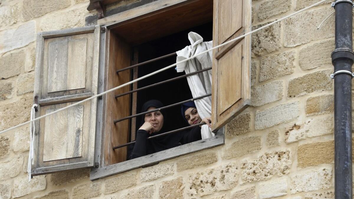 Lebanese women look out of a window during confinement at home due to the COVID-19 pandemic, in the historic part of the southern coastal city of Sidon (Saida), on April 6, 2020. Lebanon's President called on international donors to provide financial assistance to the crisis-hit country as it grapples with a severe economic downturn compounded by the novel coronavirus pandemic. JOSEPH EID / AFP
