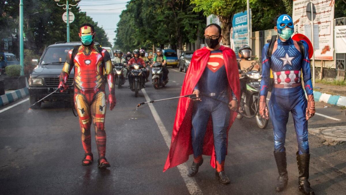 Indonesian police officers wearing superhero costumes on the street disinfect motorists' vehicles in Pasuruan, East Java on April 9, 2020, amid concert to the COVID-19 coronavirus. JUNI KRISWANTO / AFP