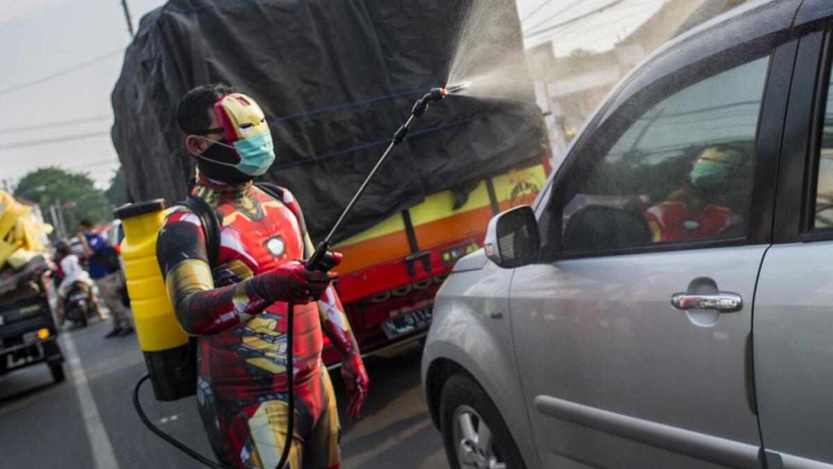 An Indonesian police officer wearing a superhero costume on the street disinfects motorists' vehicles in Pasuruan, East Java on April 9, 2020, amid concert to the COVID-19 coronavirus. JUNI KRISWANTO / AFP