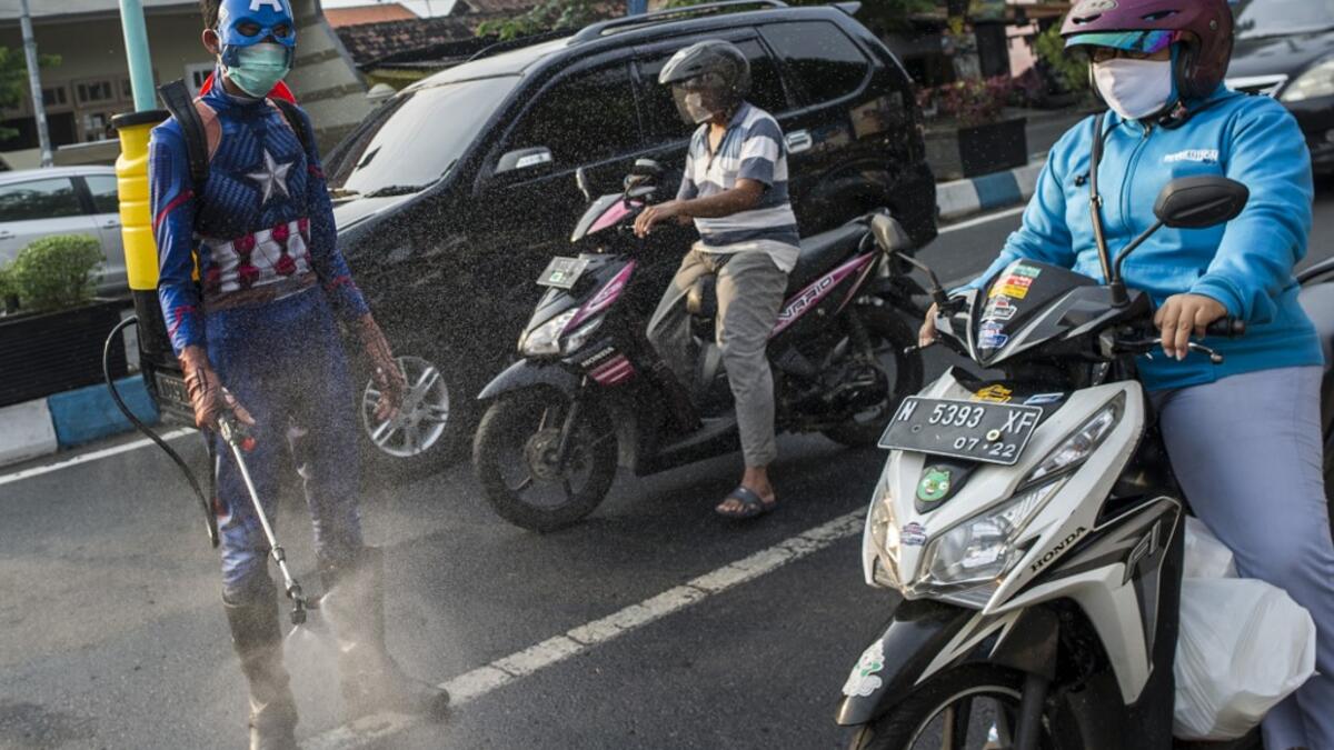 An Indonesian police officer wearing a superhero costume on the street disinfects motorists' vehicles in Pasuruan, East Java on April 9, 2020, amid concert to the COVID-19 coronavirus. JUNI KRISWANTO / AFP
