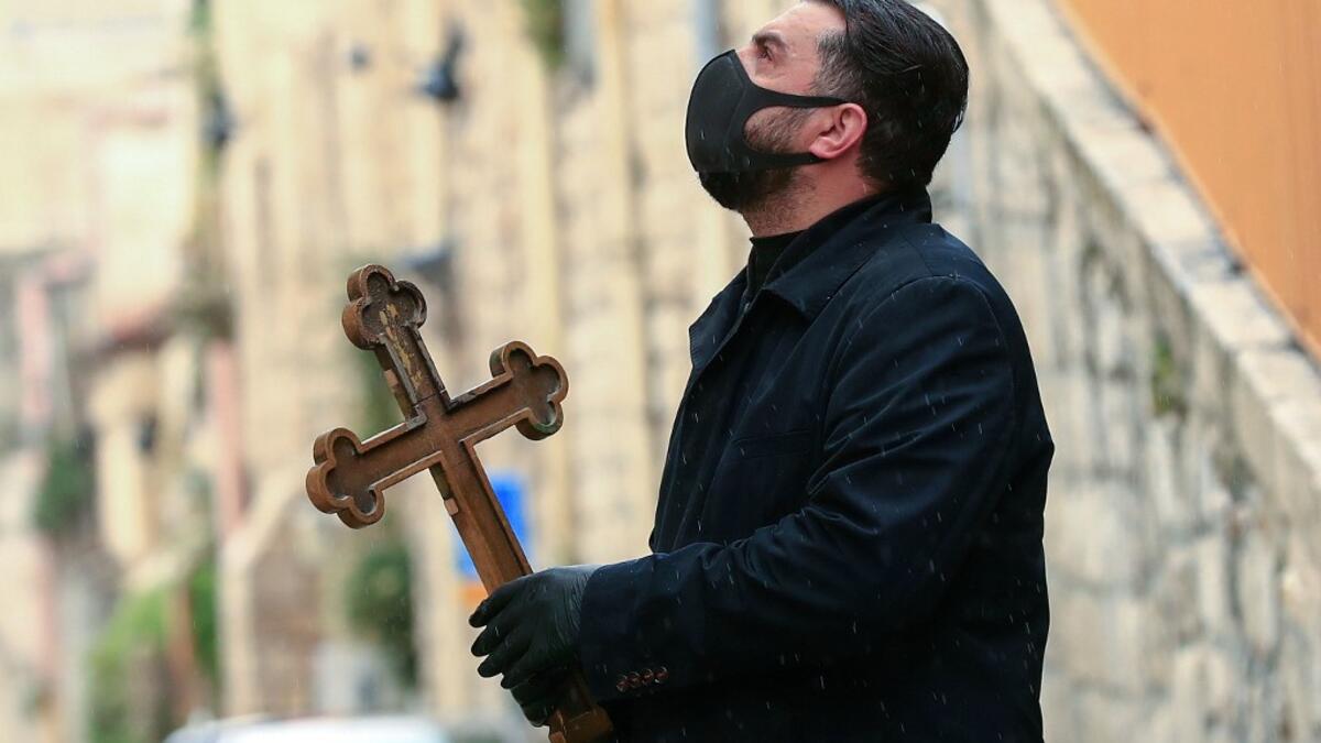 A Christian pilgrim wearing protective gear amid the COVID-19 outbreak, prays at the first station while making his way alone in the Procession of the Way of the Cross along the Via Dolorosa, to mark Good Friday in Jerusalem on April 10, 2020. All cultural sites in the Holy Land are shuttered, regardless of their religious affiliation, as authorities seek to forestall the spread of the deadly respiratory disease, which will prevent Christians from congregating for the Easter service, this coming Sunday for