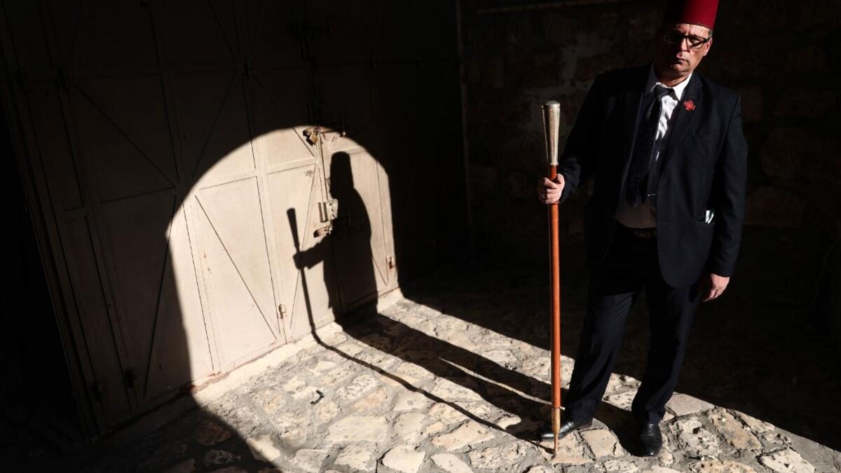 The Kawas of the Franciscan order waits for a priest by the entrance of the yard of the Church of the holy Sepulchre in Jerusalem's Old City on April 9, 2020, amid the COVID-19 pandemic. All cultural sites in the Holy Land are shuttered, regardless of their religious affiliation, as authorities seek to forestall the spread of the deadly respiratory disease, which will prevent Christians from congregating for the Easter service, this coming Sunday for Catholic worshippers, then a week later on April 19 for O
