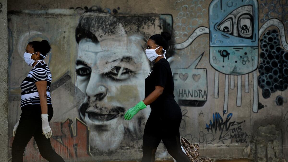 Women wearing face maskS and gloves walk along a street of Havana, on April 11, 2020. Cuba hit out at the United States on Friday over its nearly 60-year-old embargo against the island nation, which Havana described as "even more cruel" given the suffering caused by the new coronavirus pandemic. The communist-run single-party island is finding it tough to source medical supplies and has already recorded 620 coronavirus cases and 16 deaths. YAMIL LAGE / AFP