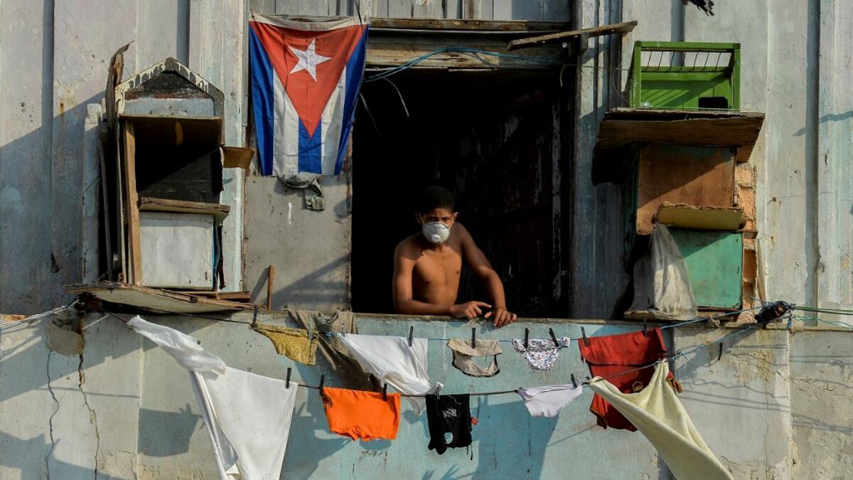 A man wears a face mask stands on his balcony in Havana, on April 11, 2020. Cuba hit out at the United States on Friday over its nearly 60-year-old embargo against the island nation, which Havana described as "even more cruel" given the suffering caused by the new coronavirus pandemic. The communist-run single-party island is finding it tough to source medical supplies and has already recorded 620 coronavirus cases and 16 deaths.