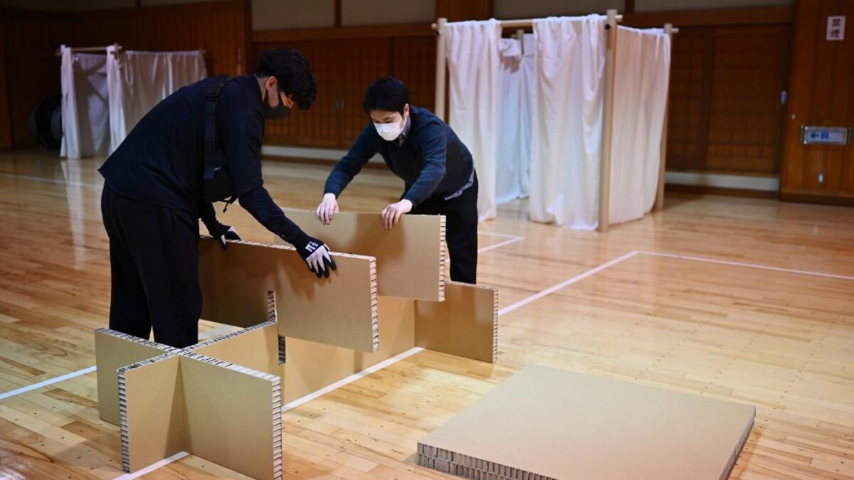 This photo taken on April 14, 2020 shows workers from Voluntary Architects' Network building partitions and beds at a shelter provided by Kanagawa prefecture for people who can’t afford to rent an apartment and used to stay at designated internet cafes, which are closed due to the COVID-19 coronavirus outbreak state of emergency, at a judo sport hall in Yokohama, Kanagawa prefecture. CHARLY TRIBALLEAU / AFP