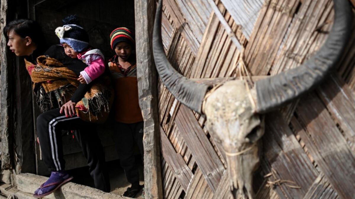 This photo taken on February 9, 2020 shows people leaving a Union Solidarity and Development Party house in Karmawlawyi village in Myanmar's Sagaing region, near the border with India. The king of the Konyak tribe sleeps in Myanmar, but eats in India -- his house, village and people divided by a mountain border which serves as a vulnerable lifeline now severed by a coronavirus lockdown.  Ye Aung THU / AFP