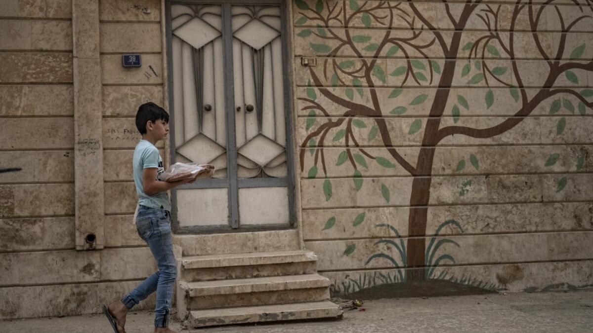A Syrian boy carries bread back to his home in the city of Qamishli in Syria's northeastern Hasakeh province on April 24, 2020, on the first day of the Muslim holy fasting month of Ramadan despite the COVID-19 coronavirus pandemic. DELIL SOULEIMAN / AFP