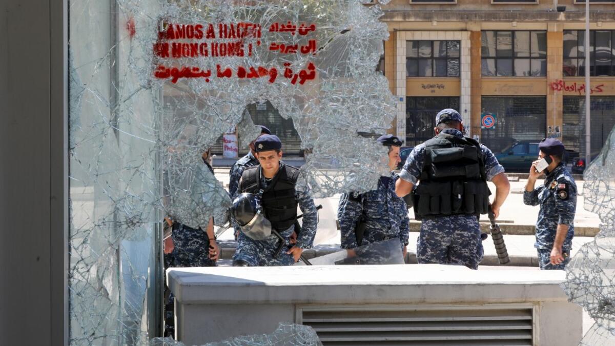 Members of the Lebanese security forces are seen through a broken store window in the downtown area of the capital Beirut, during an anti-government demonstration marking International Workers' Day (Labour Day), on May 1, 2020. ANWAR AMRO / AFP
