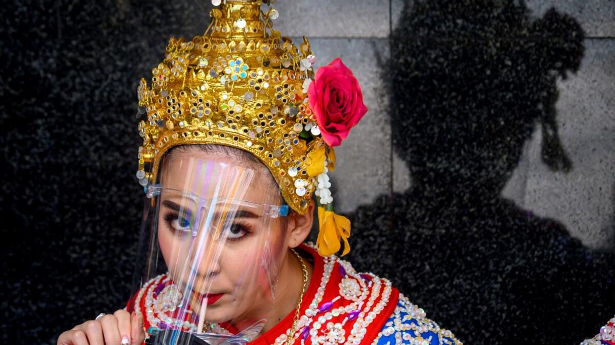 A traditional Thai dancer drinks under her protective face shield before a performance at the Erawan Shrine, which was reopened after the Thai government relaxed measures to combat the spread of the COVID-19 novel coronavirus, in Bangkok on May 4, 2020. Thailand began easing restrictions related to the COVID-19 novel coronavirus on May 3 by allowing various businesses to reopen, but warned that the stricter measures would be re-imposed should cases increase again. Mladen ANTONOV / AFP