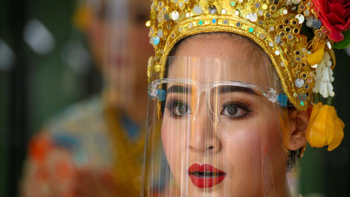A traditional Thai dancer wearing a protective face shield performs at the Erawan Shrine, which was reopened after the Thai government relaxed measures to combat the spread of the COVID-19 novel coronavirus, in Bangkok on May 4, 2020. Thailand began easing restrictions related to the COVID-19 novel coronavirus on May 3 by allowing various businesses to reopen, but warned that the stricter measures would be re-imposed should cases increase again. Mladen ANTONOV / AFP