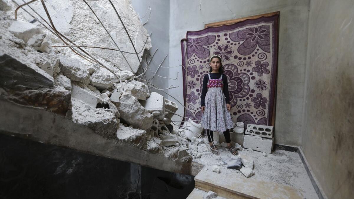 A Syrian girl whose family decided to return home for fear of the COVID-19 pandemic in packed camps for the internally displaced, poses for a picture amid the rubble in her damaged house in al-Nayrab, a village ravaged by pro-government forces bombardment near the M4 strategic highway, in Syria's northwestern Idlib province, on May 3, 2020. Bakr ALKASEM / AFP