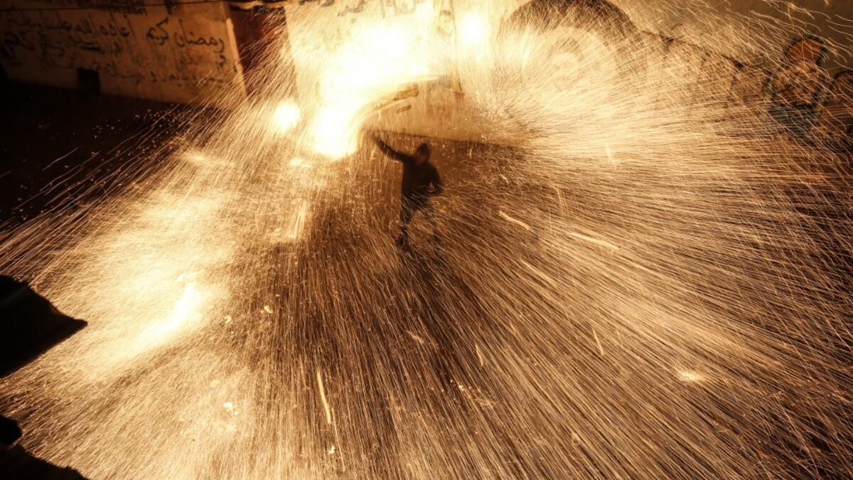 A Palestinian youth swings a homemade sparkler firework as people celebrate on a night of the Muslim holy month of Ramadan in Rafah refugee camp, in the southern Gaza Strip, on May 4, 2020. MAHMUD HAMS / AFP