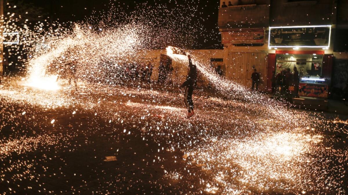 A Palestinian youth swings a homemade sparkler firework as people celebrate on a night of the Muslim holy month of Ramadan in Rafah refugee camp, in the southern Gaza Strip, on May 4, 2020. MAHMUD HAMS / AFP