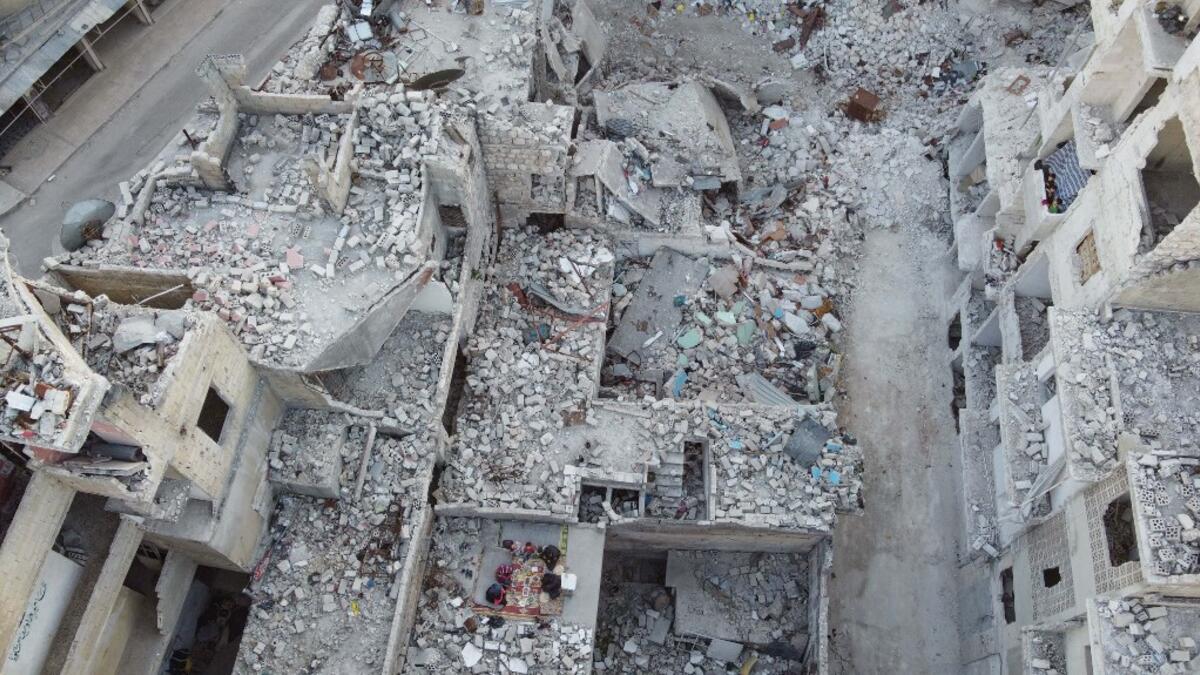 This picture taken on May 4, 2020 during the Muslim holy fasting month of Ramadan shows an aerial view of members of the displaced Syrian family of Tareq Abu Ziad, from the town of Ariha in the southern countryside of the Idlib province, breaking their fast together for the sunset "iftar" meal, in the midst of the rubble of their destroyed home upon their return to the town for one day after fleeing during the previous military assault by Syrian government forces and their allies. Aaref WATAD / AFP