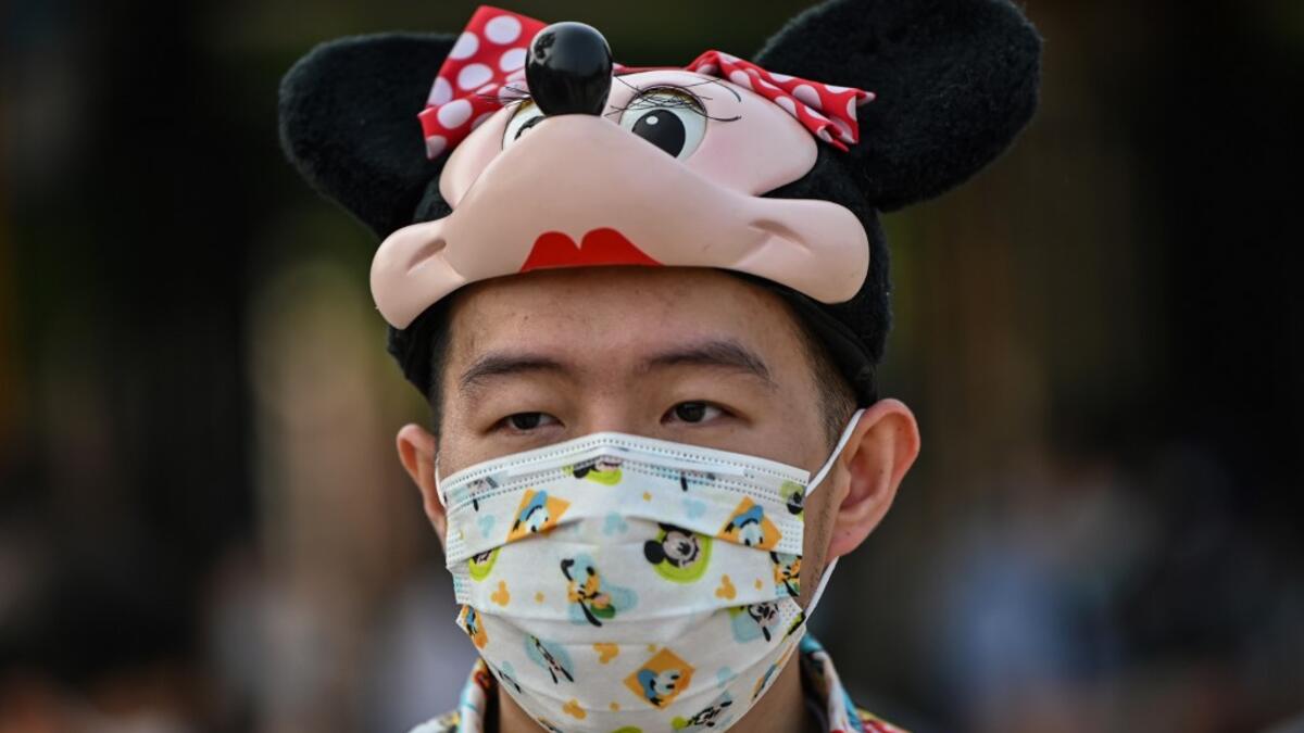 A man fan wearing a face mask waits to enter the Disneyland amusement park in Shanghai on May 11, 2020. Disneyland Shanghai reopened on May 11 to the public after being closed since January due to the COVID-19 coronavirus outbreak. Hector RETAMAL / AFP