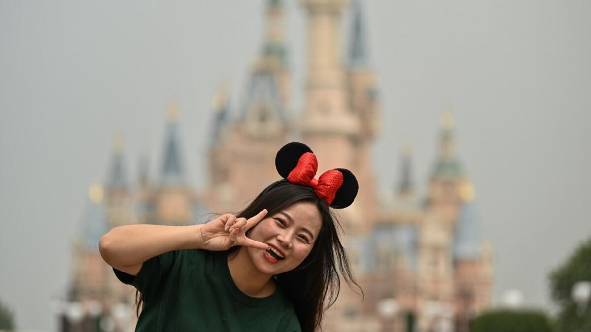 A woman gestures while visiting the Disneyland amusement park in Shanghai on May 11, 2020. Disneyland Shanghai reopened on May 11 to the public after being closed since January due to the COVID-19 coronavirus outbreak. Hector RETAMAL / AFP