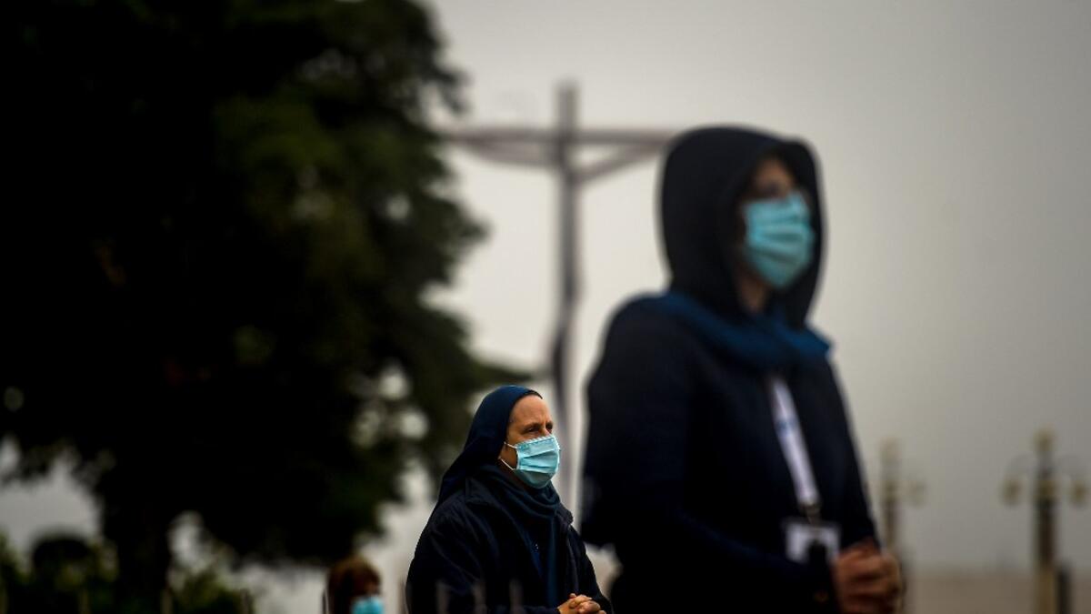 People wearing face masks and keeping their social distance, attend the 103rd anniversary of the apparitions of Our Lady of Fatima at the Fatima shrine in central Portugal on May 13, 2020. Without the crowd of pilgrims it welcomes every year, the shrine of Fatima celebrated the anniversary during a religious ceremony reduced to the bare minimum. PATRICIA DE MELO MOREIRA / AFP