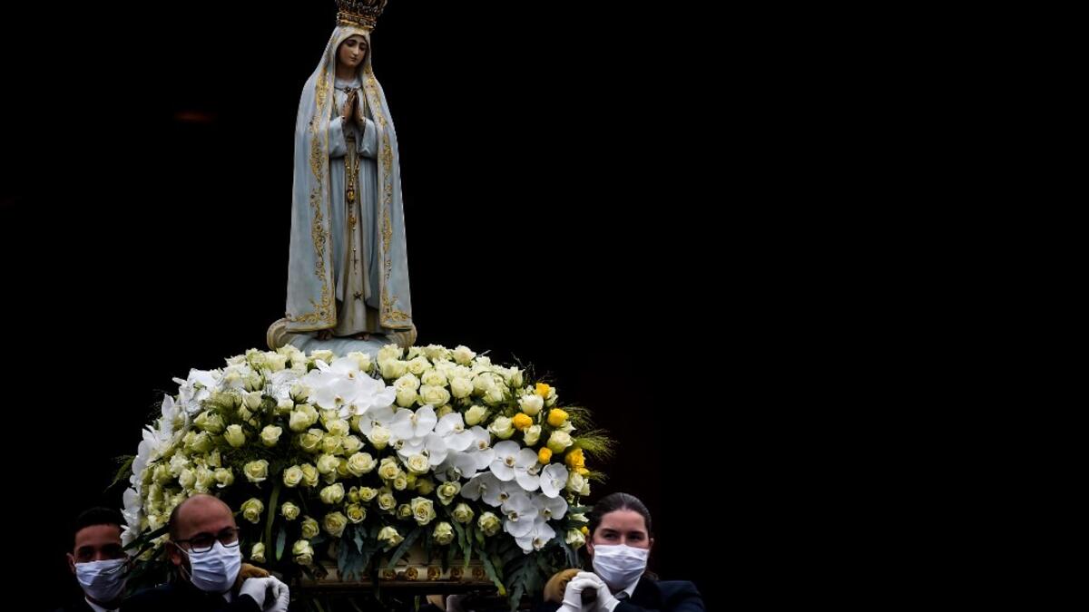 The statue of Our Lady Fatima is carried by people wearing face masks during the 103rd anniversary of the apparitions of Our Lady Fatima at the Fatima shrine in central Portugal on May 13, 2020. Without the crowd of pilgrims it welcomes every year, the shrine of Fatima celebrated the anniversary during a religious ceremony reduced to the bare minimum. PATRICIA DE MELO MOREIRA / AFP
