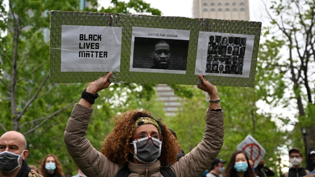 A woman is holding a Black Lives Matter placard asking for Justice for George and other victims of racism and police brutalities on Montreal's Place du Canada on May 31, 2020. Several thousands demonstrators marched on Sunday in central Montreal against racism and police violence, in solidarity with demonstrations in the United States following the death of George Floyd. Eric THOMAS / AFP