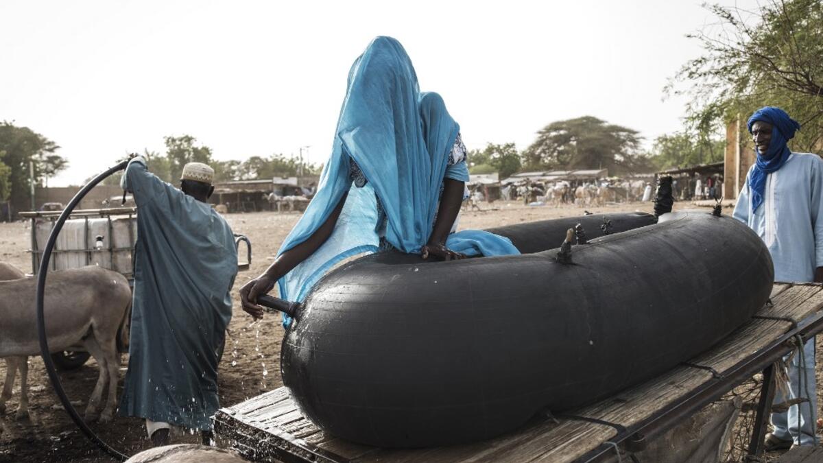Fulani herders fill up their water tanks to take back to their camp at a unofficial herders market in Barkedji on May 28, 2020. Access to water comes at a price, many families must travel up to ten kilometres everyday to fill up their water supply, which then will be used for their livestock and themselves. COVID-19 coronavirus restrictions have closed down markets and regional movement, as a result Fulani herders are struggling to move to areas with more grazing land for there live stock. JOHN WESSELS / AF