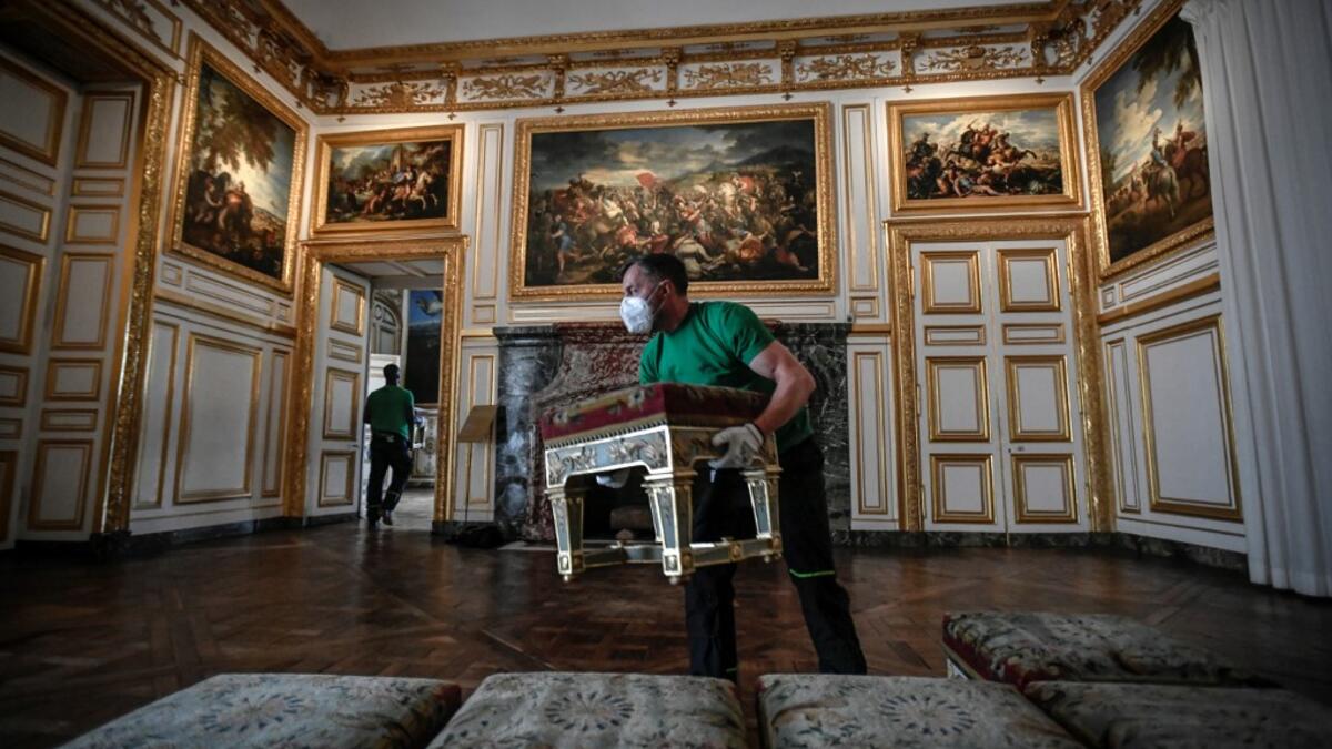 A worker carries furniture in the Galerie des Glaces (Hall of Mirrors) at the Chateau de Versailles (Palace of Versailles) in Versailles near Paris, on June 5, 2020 on the eve of it re-opening after 82 days of closure due to the novel coronavirus (COVID-19) outbreak. The Palace of Versailles -- France's big tourist attraction with nearly 10 million tourists a year - will open on June 6 with no US or Asia tourists who represent 30% of its visitors. STEPHANE DE SAKUTIN / AFP