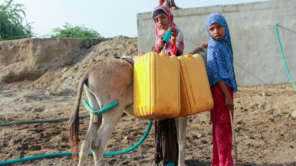 Yemeni girls fill jerrycans carried by donkeys with water from a cistern at a make-shift camp for the internally displaced, in the northern Hajjah province, on June 7, 2020, amid a severe shortage of water. ESSA AHMED / AFP
