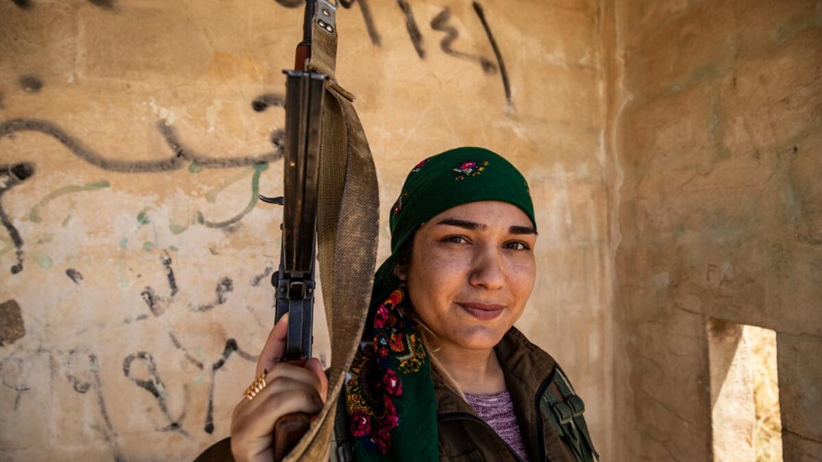 A Kurdish female volunteer, from the newly formed Community Protection Forces, guards a wheat field, against threats by jihadists to burn the crops, during harvest season on June 13, 2020, in the countryside east of Qamishli in Syria's northeastern Hasakah province. Delil SOULEIMAN / AFP
