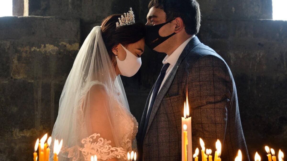 A bride and a bridegroom wearing protective face masks exchange kisses during a wedding ceremony in a church in the Saghmosavan village outside Yerevan on June 14, 2020, as the country tries to curb the spread of the COVID-19, the disease caused by the novel coronavirus. Karen MINASYAN / AFP