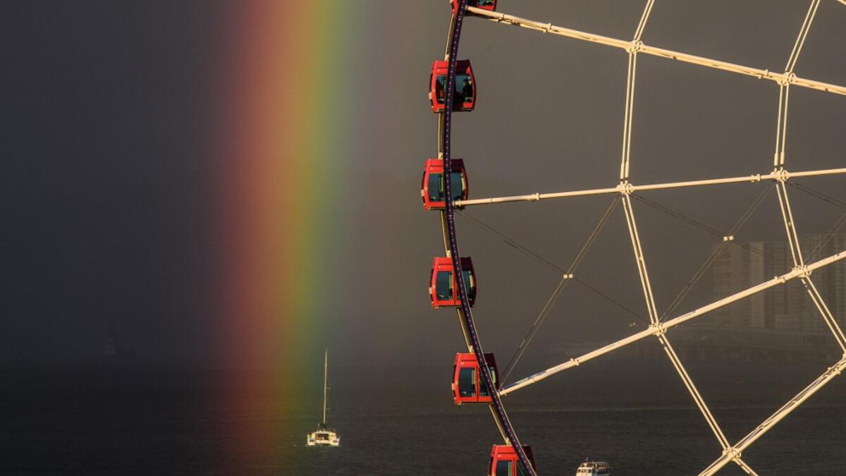 Passengers (top C) sit in a ferris wheel as a rainbow appears during sunset after a rain shower in Hong Kong on June 16, 2020. Anthony WALLACE / AFP