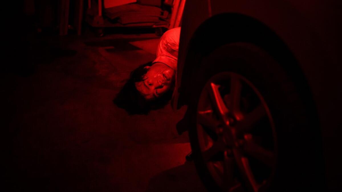 This picture taken on June 15, 2020 shows actor Kota Hanegawa, 28, acting as a victim during a demonstration of a haunted house at a garage in Tokyo. A car horn beeps and the horror begins: a bloody murder and rampaging zombies. But this drive-in haunted house in Japan protects against the most terrifying enemy of all -- coronavirus. Inside a car, guests can scream as loudly as they like, with no mask required, as hideous creatures daubed in blood swarm towards them.  Philip FONG / AFP