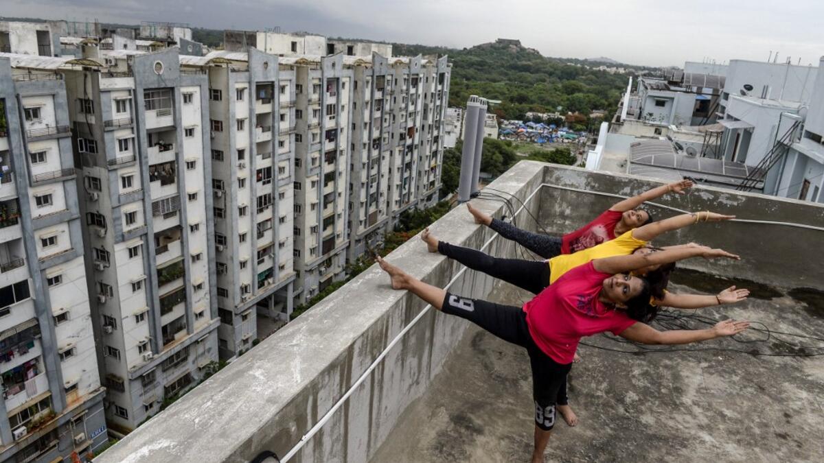 Yoga instructors from Anahata Yoga Zone perform yoga postures on a building's terrace in Hyderabad on June 18, 2020, ahead of the International Yoga Day annually celebrated on June 21. NOAH SEELAM / AFP