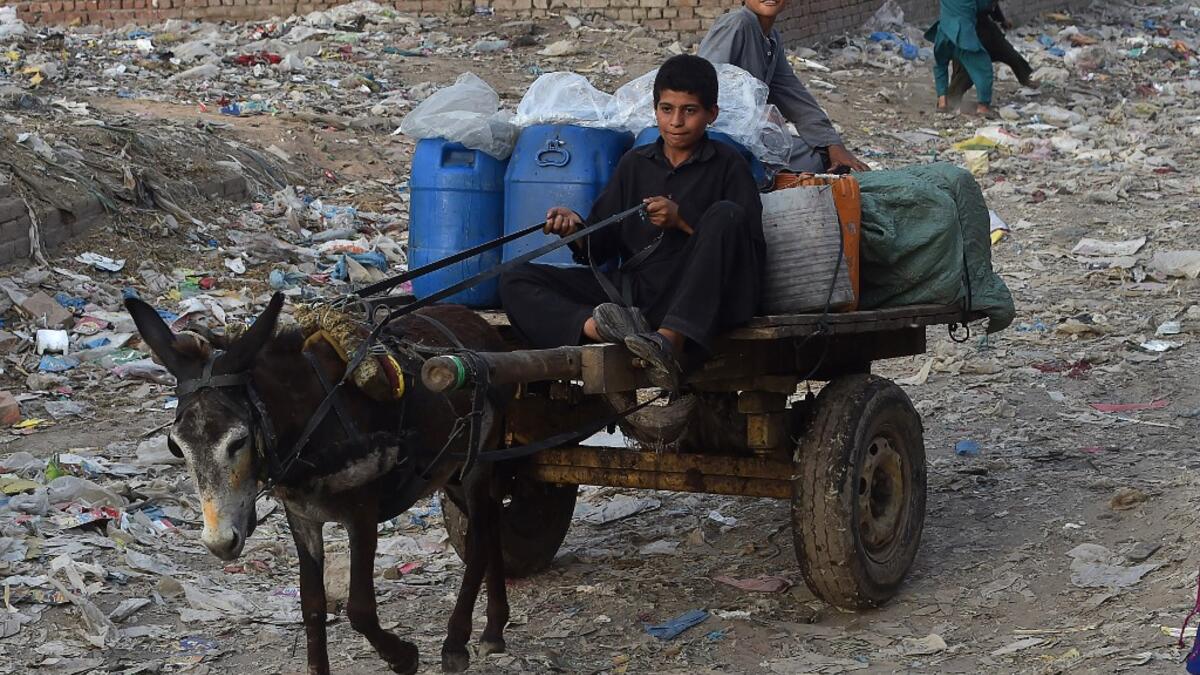 Children of Afghan refugees ride on a donkey cart at a slum area in Lahore on June 19, 2020, ahead of the World Refugees Day. Arif ALI / AFP