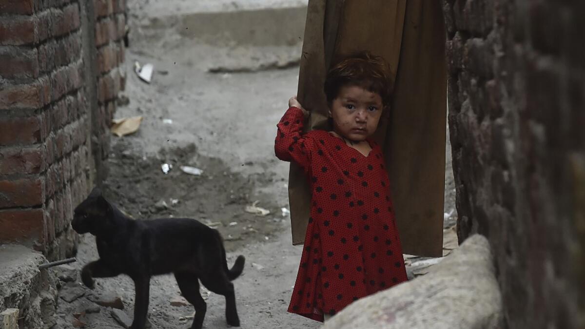 A child of an Afghan refugee stands near a cat at a slum area in Lahore on June 19, 2020, ahead of the World Refugees Day. Arif ALI / AFP
