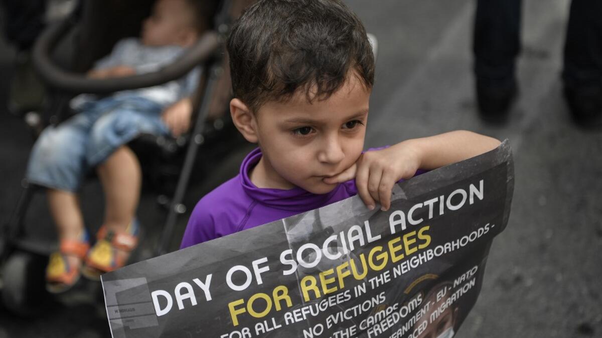 A young child holds a poster as he joins refugees participating in a rally in Athens on June 20, 2020, marking World Refugee Day aS THEY demand rights and housing for refugees and migrants in Greece. Louisa GOULIAMAKI / AFP