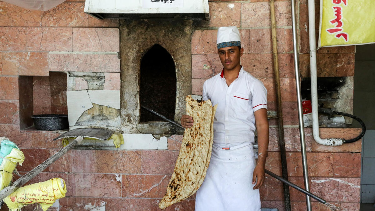 Ali, 21, an Iranian baker poses with Sangak bread in the capital Tehran on June 13, 2020. ATTA KENARE / AFP