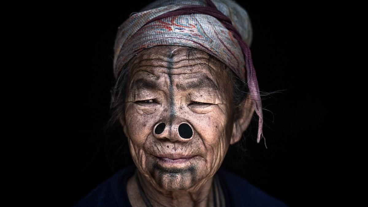 Striking images reveal the distinctive facial features of the Konyak tribe from North Eastern India, thought to be over 80 years old. A woman sporting two nose plugs and black markings across her face gazes wistfully out of the shot. (Mediadrumimages/ Trevor Cole)